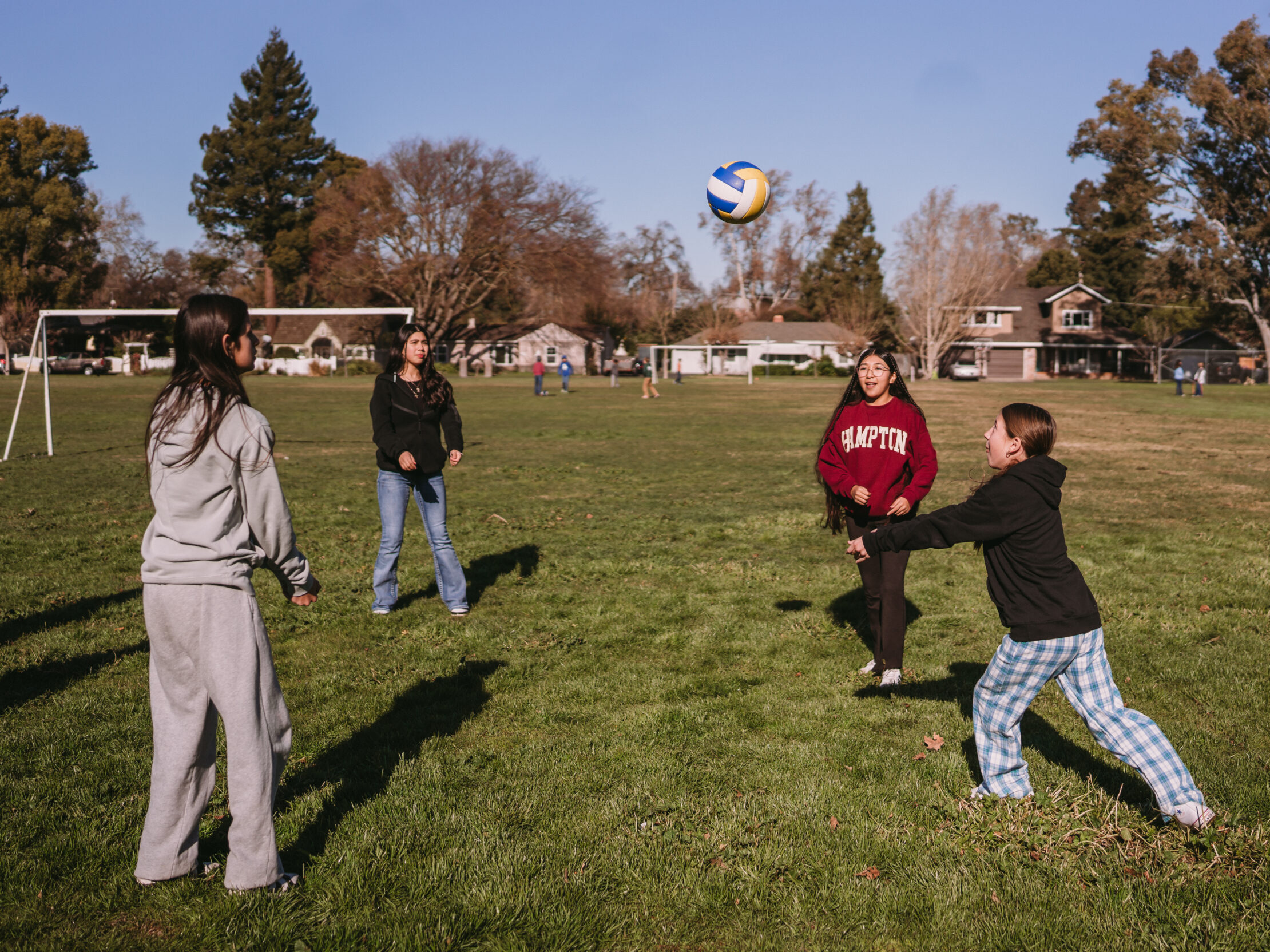Four girls bumping a vollyball back and forth amongst their group.