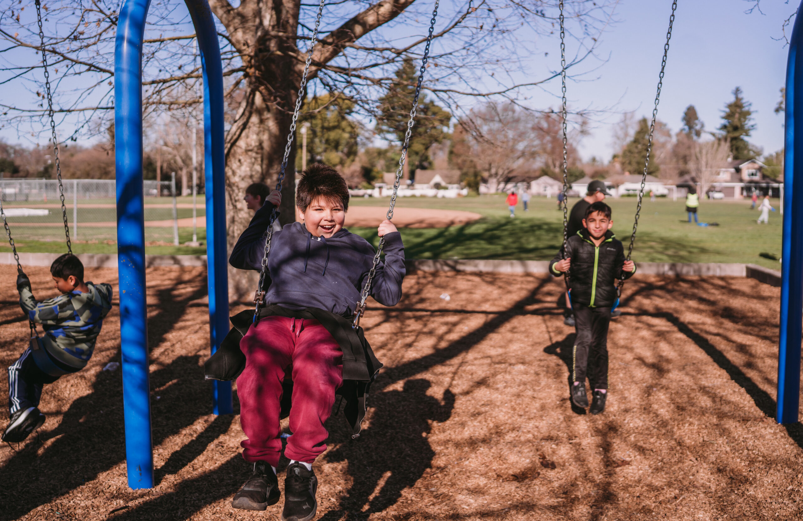 Two boys happily swinging on swings in the school playground.